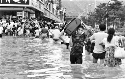 昨日，一名消防戰(zhàn)士在秦皇島市山海關(guān)火車站站前廣場(chǎng)涉水幫助旅客運(yùn)送行李。 新華社發(fā)