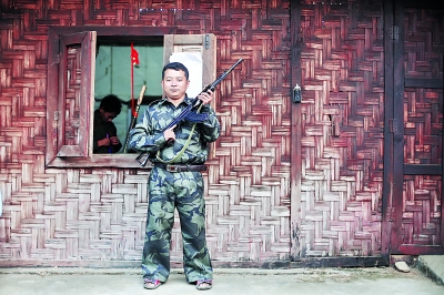 老三手持自己在前線用的半自動(dòng)步槍站在居住的小屋外。